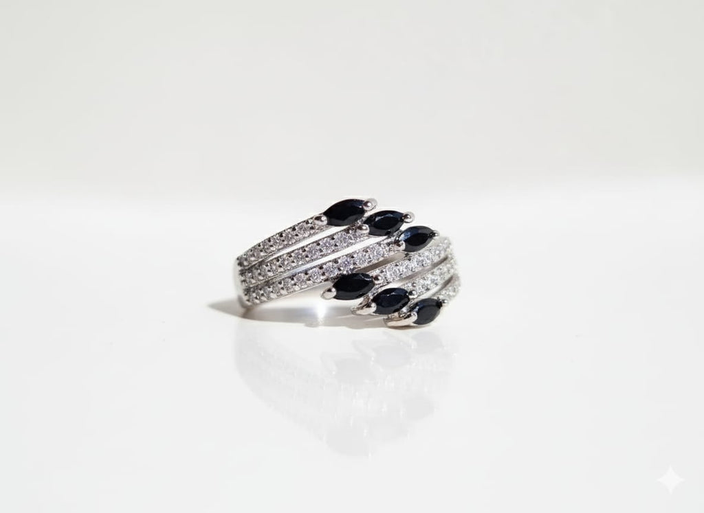 Silver ring with black gemstones on a white background
